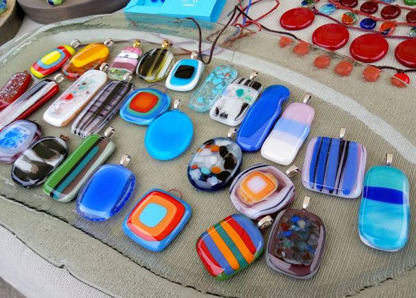 A collection of colorful handcrafted glass pendants with various patterns and designs.